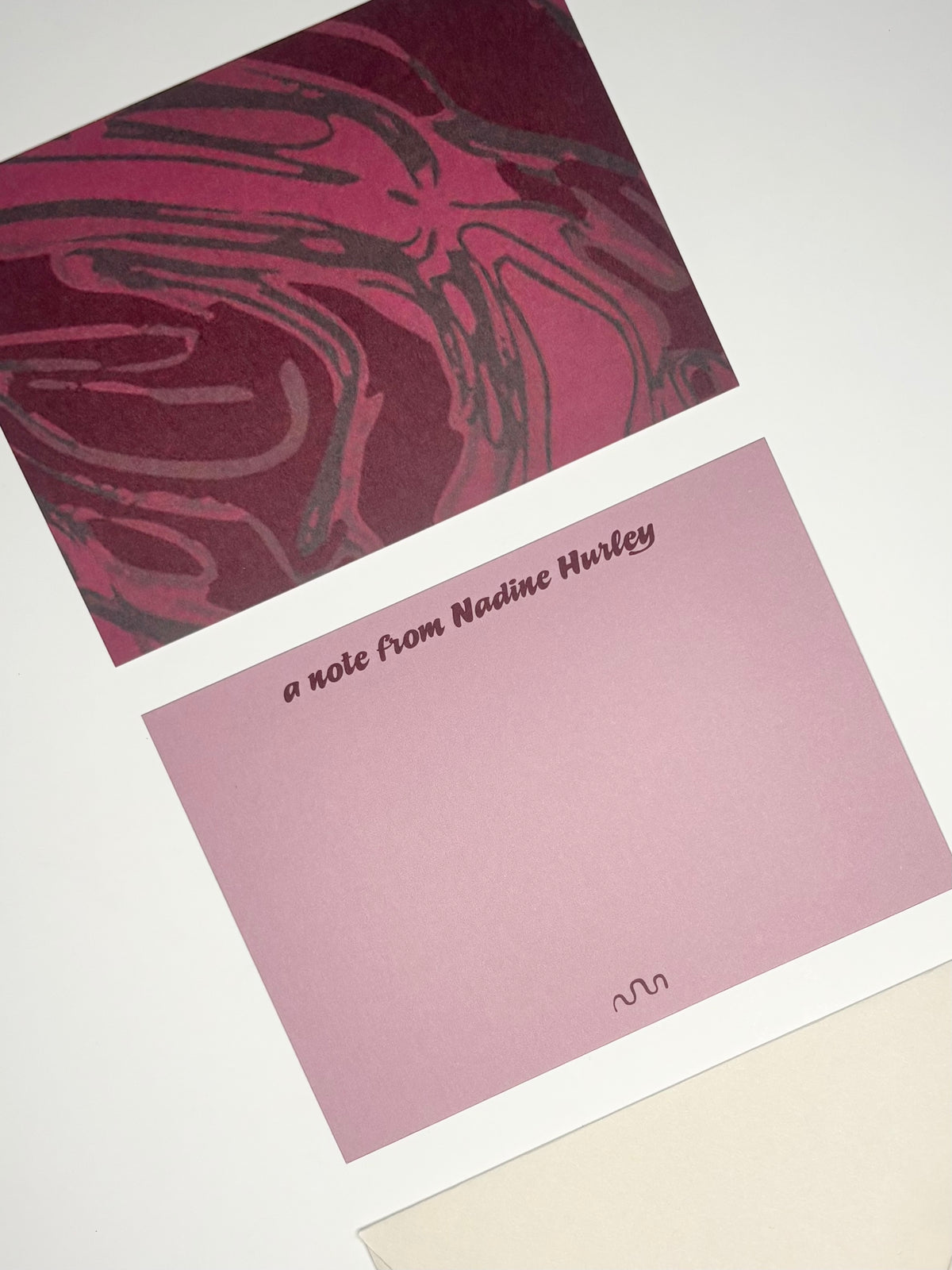 Close-up of Oxbow stationery showing a deep wine purple and pink river pattern with a personalized purple writing side.