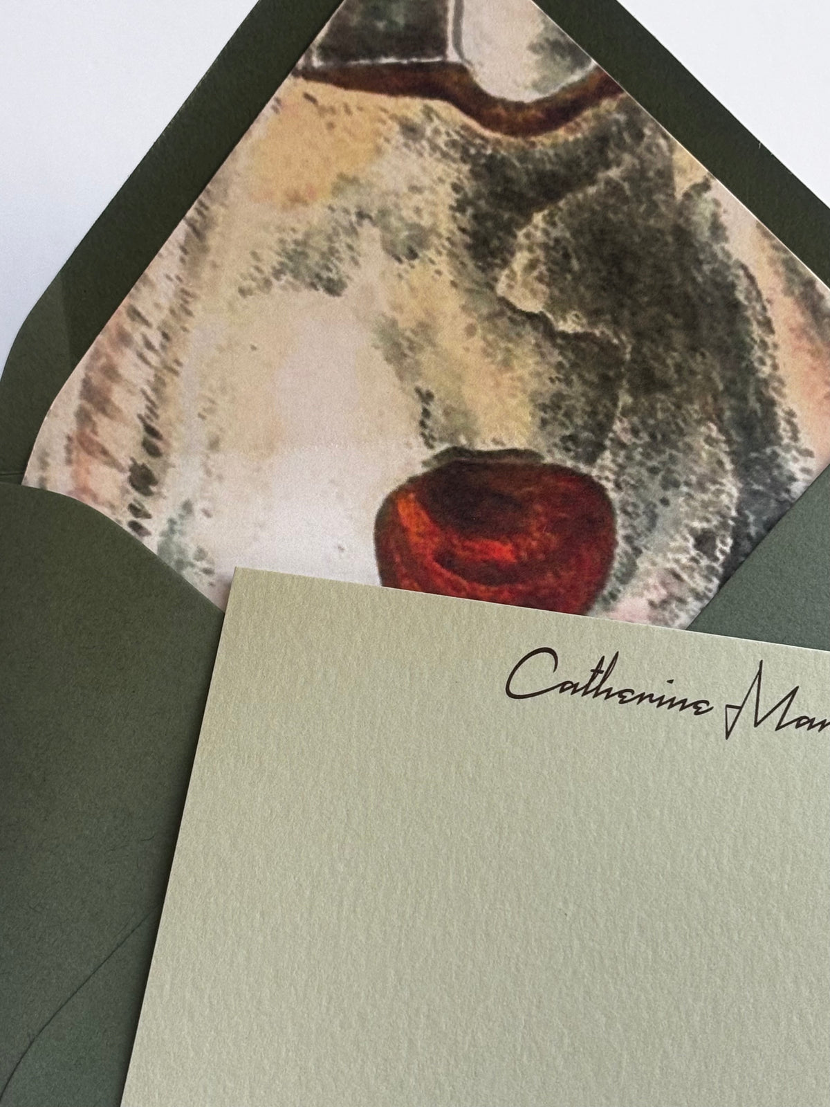 Close-up of The Half Shell stationery showing personalized script and the envelope’s oyster shell liner with a red accent.