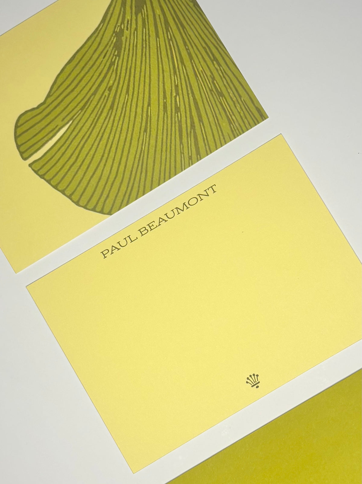 Close-up of yellow personalized stationery showing the name Paul Beaumont and an oversized green fan-shaped leaf design.