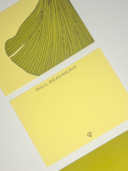 Close-up of yellow personalized stationery showing the name Paul Beaumont and an oversized green fan-shaped leaf design.