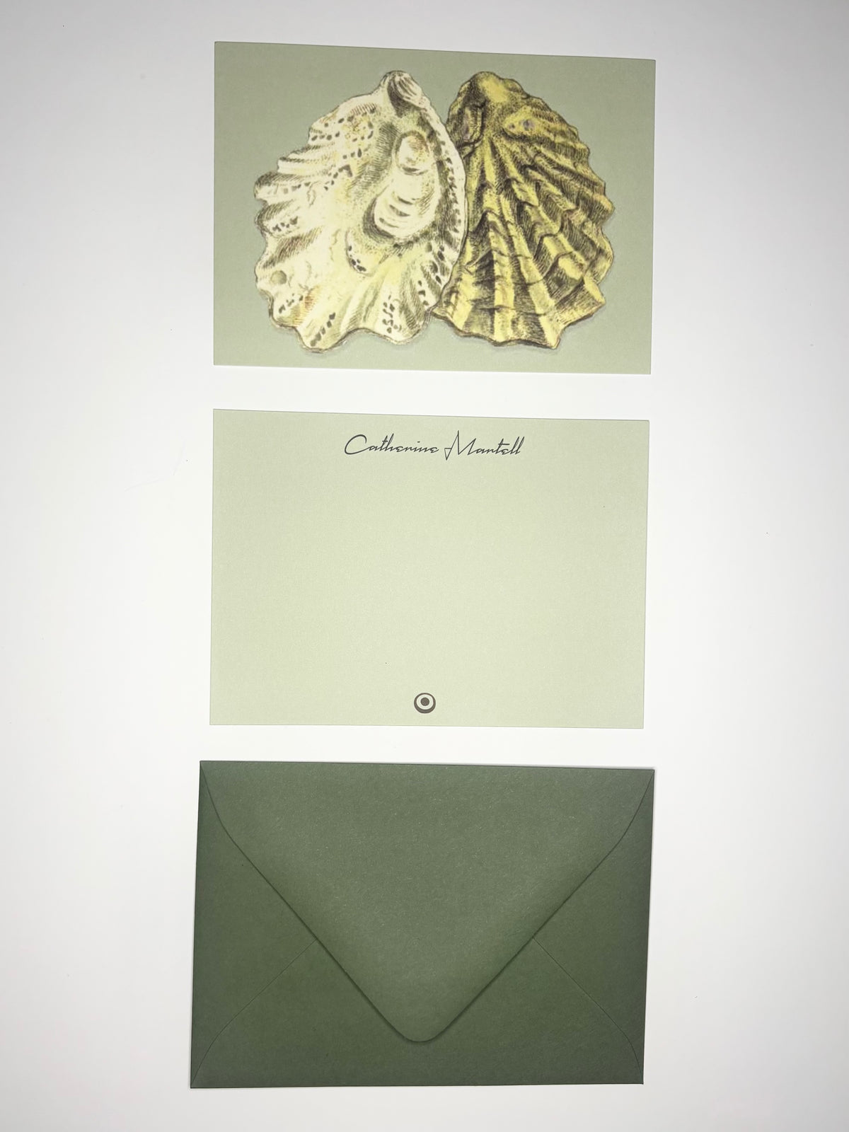 Oyster Shells stationery set showing a shell-illustrated back, personalized pale green front, and dark green envelope.