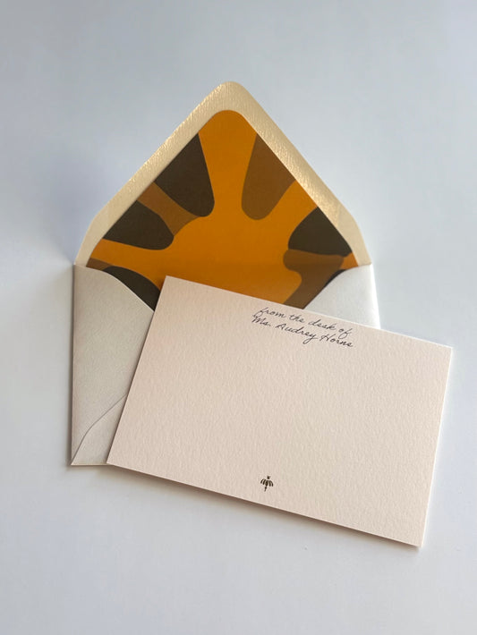 Poppy personalized blush notecard with an open cream envelope lined in a bold gold and green floral design.