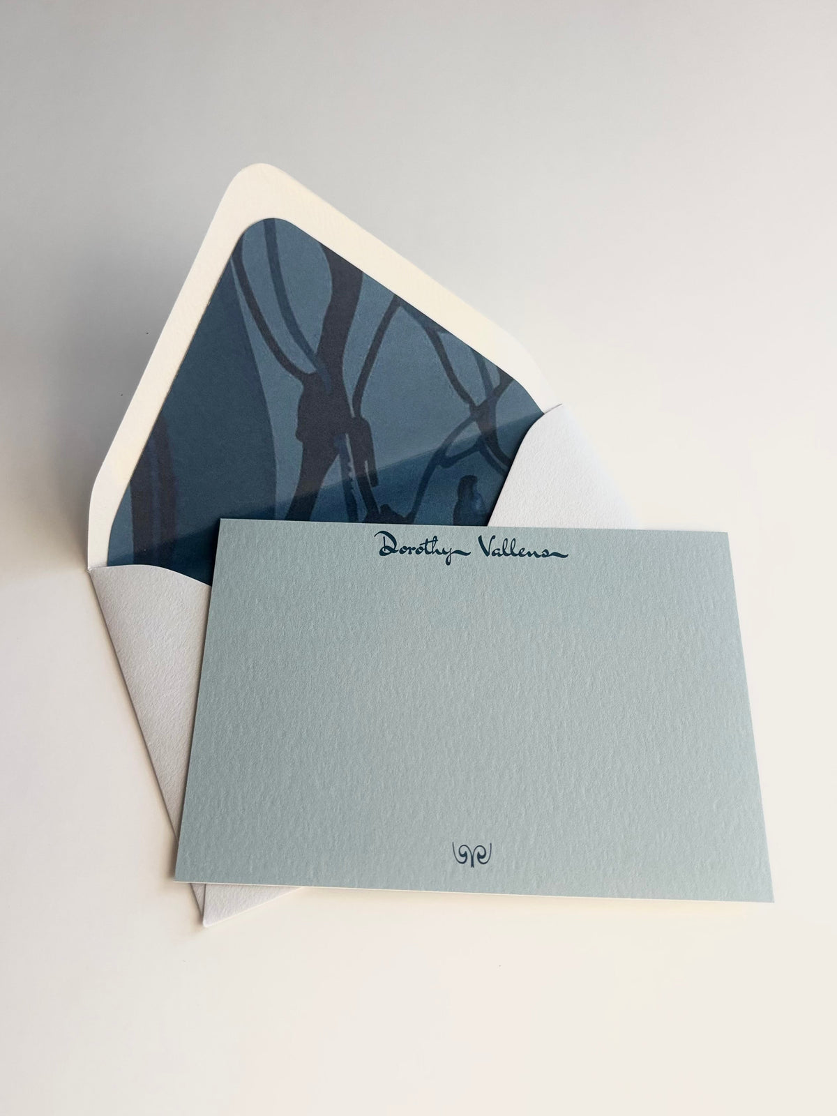 The Fall Line personalized pale blue notecard with an open cream envelope lined in a dark blue map-inspired pattern.