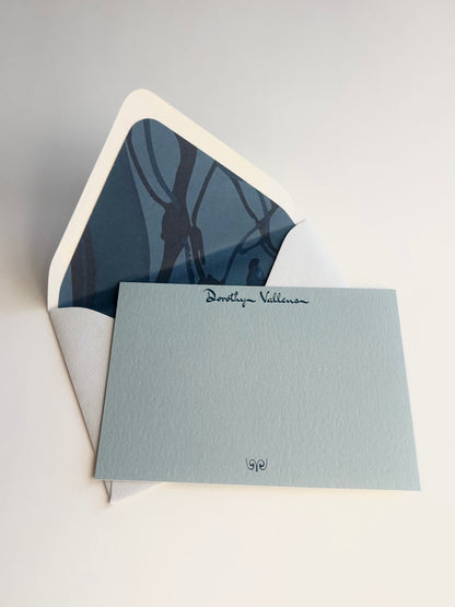 The Fall Line personalized pale blue notecard with an open cream envelope lined in a dark blue map-inspired pattern.