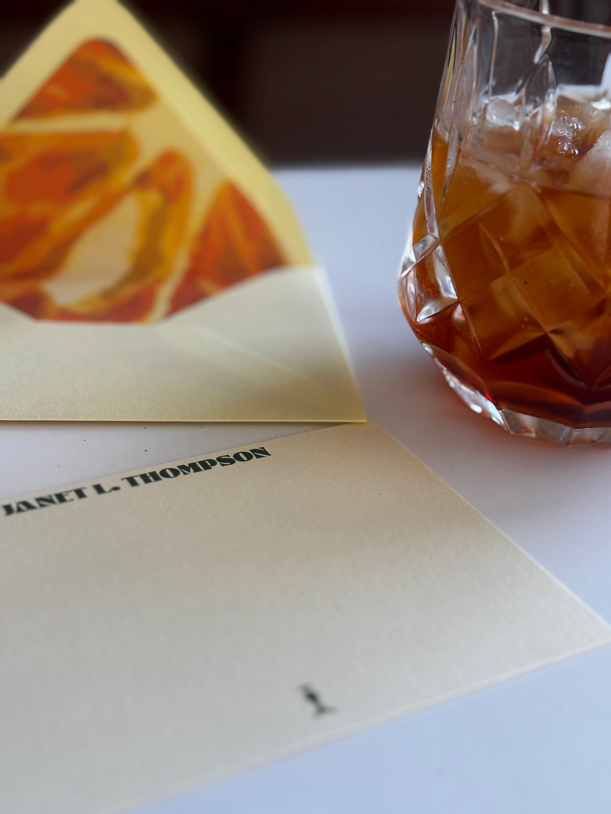 Orange You Glad personalized notecard and orange slice-lined envelope beside an old fashioned.