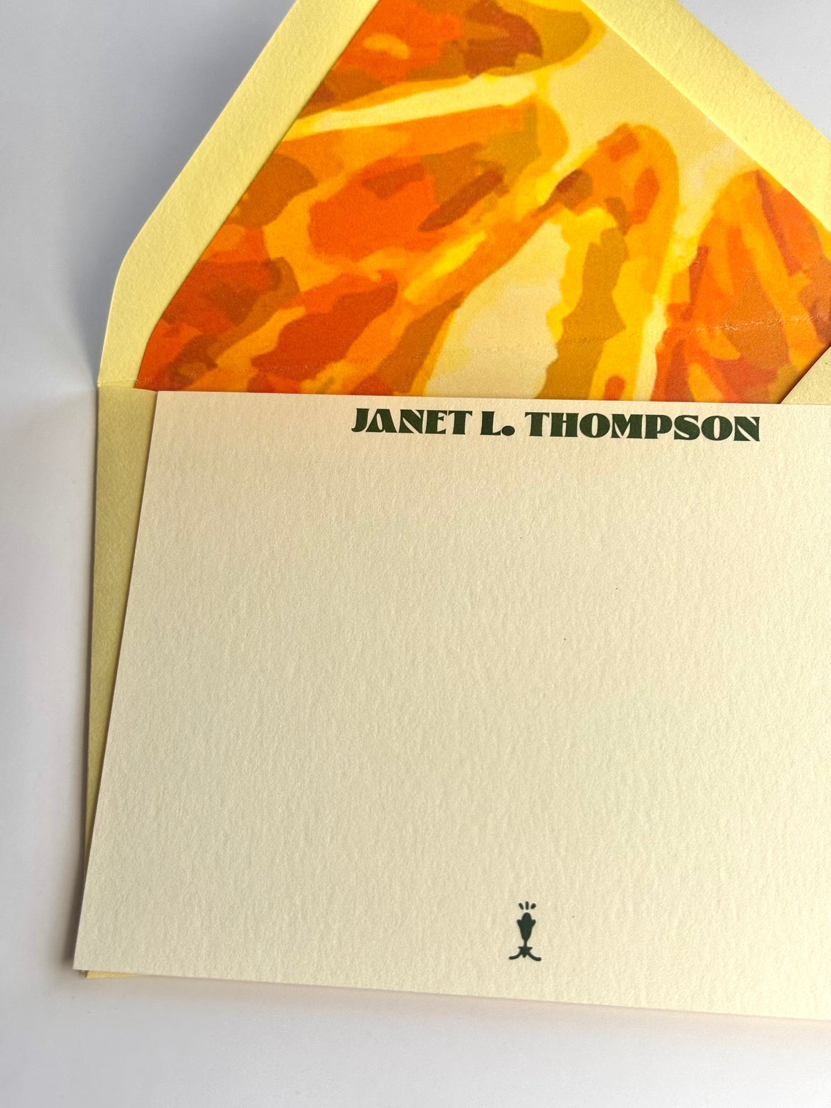 Close-up of Orange You Glad stationery showing personalized lettering and the envelope’s bright orange slice liner.