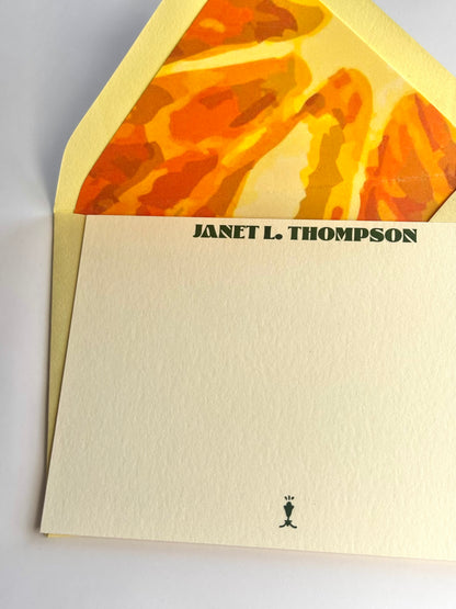 Close-up of Orange You Glad stationery showing personalized lettering and the envelope’s bright orange slice liner.